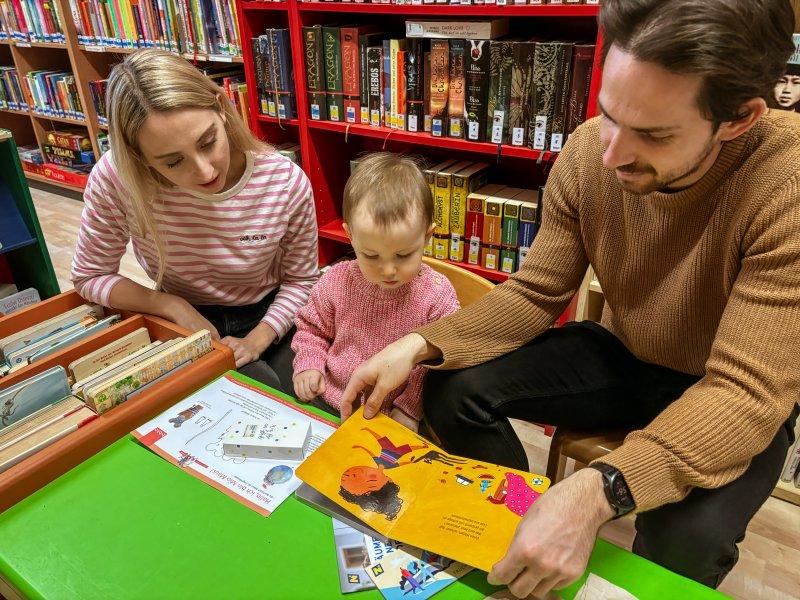 Eltern mit Kind schauen Buchstarttasche an